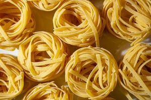 Uncooked Egg-Based Fettuccine Pasta. A Culinary Canvas of Ribbon-Shaped Macaroni, Creating a Lively and Textured Background for Gourmet Cooking. Dry Pasta. Raw Macaroni - Top View, Flat Lay photo