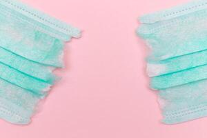 Anti Mask Movement - Green Torn Medical Face Mask on the Pink Background. Pandemic and Lockdown End - Top View, Flat Lay photo