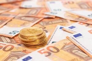 A Stack of Bitcoin Coins on the 50 Euro Banknotes. Euro Currency and Crypto Currency. Orange Paper Money. A Lot of Fifty-Euro Bills. Finances, Cash, Anonymous Payments and Money Saving Concept photo