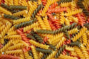 Uncooked Vibrant Colored Fusilli Pasta. A Mesmerizing Culinary Canvas of Multicolored Spirals, Creating a Lively and Textured Background for Gourmet Cooking. Colored Dry Pasta. Raw Macaroni photo