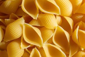 Uncooked Conchiglie Pasta. A Culinary Canvas of Conchiglie Macaroni, Creating a Lively and Textured Background for Gourmet Cooking. Dry Pasta. Raw Macaroni - Top View, Flat Lay photo