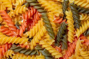 Uncooked Vibrant Colored Fusilli Pasta. A Mesmerizing Culinary Canvas of Multicolored Spirals, Creating a Lively and Textured Background for Gourmet Cooking. Colored Dry Pasta. Raw Macaroni photo