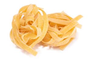 Two Classic Italian Raw Egg Fettuccine - Isolated on White Background. Dry Twisted Uncooked Pasta. Italian Culture and Cuisine. Raw Golden Macaroni Pattern - Isolation photo