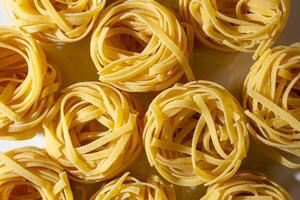 Uncooked Egg-Based Fettuccine Pasta. A Culinary Canvas of Ribbon-Shaped Macaroni, Creating a Lively and Textured Background for Gourmet Cooking. Dry Pasta. Raw Macaroni - Top View, Flat Lay photo