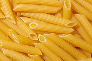 Uncooked Penne Rigate Pasta. A Culinary Canvas of Penne Macaroni, Creating a Lively and Textured Background for Gourmet Cooking. Dry Pasta. Raw Macaroni - Top View, Flat Lay photo