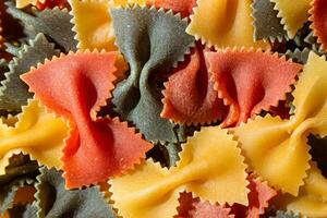 Uncooked Vibrant Colored Farfalle Pasta. A Culinary Canvas of Multicolored Bow-Tie Macaroni, Creating a Lively and Textured Background for Gourmet Cooking Enthusiasts. Colored Dry Pasta. Raw Macaroni photo