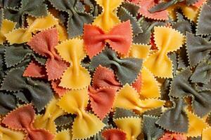 Uncooked Vibrant Colored Farfalle Pasta. A Culinary Canvas of Multicolored Bow-Tie Macaroni, Creating a Lively and Textured Background for Gourmet Cooking Enthusiasts. Colored Dry Pasta. Raw Macaroni photo