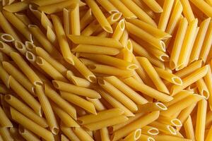 Uncooked Penne Rigate Pasta. A Culinary Canvas of Penne Macaroni, Creating a Lively and Textured Background for Gourmet Cooking. Dry Pasta. Raw Macaroni - Top View, Flat Lay photo