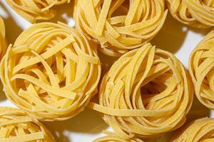 Uncooked Egg-Based Fettuccine Pasta. A Culinary Canvas of Ribbon-Shaped Macaroni, Creating a Lively and Textured Background for Gourmet Cooking. Dry Pasta. Raw Macaroni - Top View, Flat Lay photo