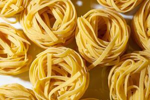 Uncooked Egg-Based Fettuccine Pasta. A Culinary Canvas of Ribbon-Shaped Macaroni, Creating a Lively and Textured Background for Gourmet Cooking. Dry Pasta. Raw Macaroni - Top View, Flat Lay photo