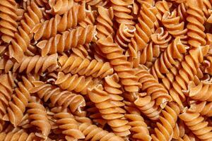Uncooked Whole Grain Fusilli Pasta. A Culinary Canvas of Whole Wheat Spirals, Creating a Lively and Textured Background for Gourmet Cooking. Whole Grain Twisted Dry Pasta. Whole Wheat Raw Macaroni photo