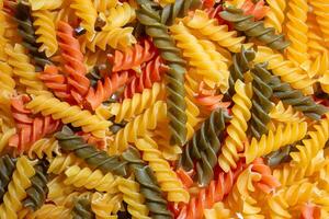 Uncooked Vibrant Colored Fusilli Pasta. A Mesmerizing Culinary Canvas of Multicolored Spirals, Creating a Lively and Textured Background for Gourmet Cooking. Colored Dry Pasta. Raw Macaroni photo