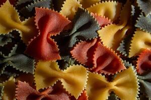 Uncooked Vibrant Colored Farfalle Pasta. A Culinary Canvas of Multicolored Bow-Tie Macaroni, Creating a Lively and Textured Background for Gourmet Cooking Enthusiasts. Colored Dry Pasta. Raw Macaroni photo