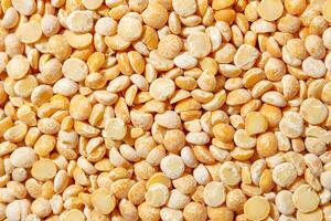 Uncooked Polished Split Peas Background. A Culinary Canvas of Dry Yellow Peas, Creating a Lively and Textured Background for Gourmet Cooking. Scattered Raw Polished Peas. Healthy Eating Ingredients photo