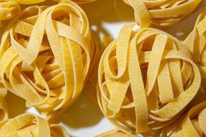Uncooked Egg-Based Fettuccine Pasta. A Culinary Canvas of Ribbon-Shaped Macaroni, Creating a Lively and Textured Background for Gourmet Cooking. Dry Pasta. Raw Macaroni - Top View, Flat Lay photo