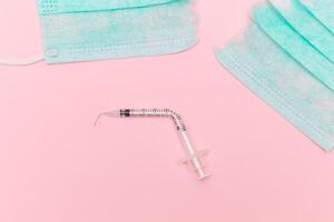 Anti Vaccine Movement and Anti Mask Concept - Broken Medical Syringe and Green Torn Medical Face Mask on the Pink Background. Pandemic and Lockdown End - Top View, Flat Lay photo