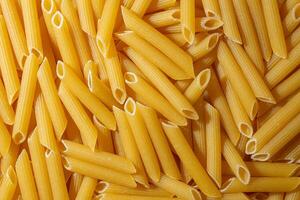 Uncooked Penne Rigate Pasta. A Culinary Canvas of Penne Macaroni, Creating a Lively and Textured Background for Gourmet Cooking. Dry Pasta. Raw Macaroni - Top View, Flat Lay photo