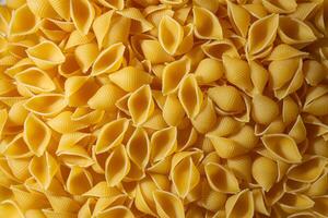 Uncooked Conchiglie Pasta. A Culinary Canvas of Conchiglie Macaroni, Creating a Lively and Textured Background for Gourmet Cooking. Dry Pasta. Raw Macaroni - Top View, Flat Lay photo