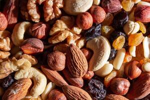 Mixed Nuts. Almonds, Walnuts, Cashews, Peanuts, Hazelnuts, Dried Prunes and Raisins. Different Nut Mix. Background from Various Nuts and Dried Fruits photo