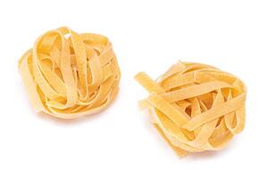 Two Classic Italian Raw Egg Fettuccine - Isolated on White Background. Dry Twisted Uncooked Pasta. Italian Culture and Cuisine. Raw Golden Macaroni Pattern - Isolation photo
