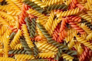 Uncooked Vibrant Colored Fusilli Pasta. A Mesmerizing Culinary Canvas of Multicolored Spirals, Creating a Lively and Textured Background for Gourmet Cooking. Colored Dry Pasta. Raw Macaroni photo