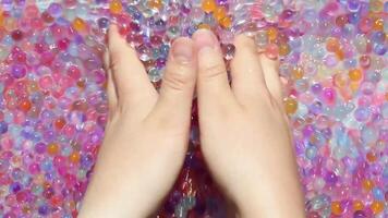 The girl's hands are slowly picking up of colorful hydrogel balls. Part 1. Asmr. video