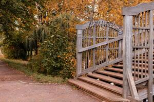 An old wooden bridge. Autumn Park. Yellow leaves on trees photo