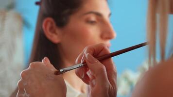 Makeup Artist Demonstrates Professional Techniques in a Studio Setting With a Model in Focus video