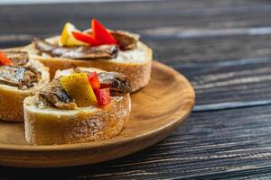 fish sandwich with butter and sprats lemon on a wooden plate, side view close up photo