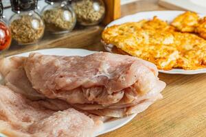 the process of cooking chicken chops with already fried chops in the background photo
