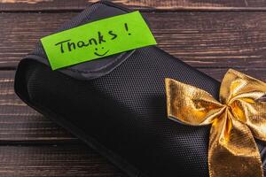 A black soft box with a green thank you label and a gold bow photo