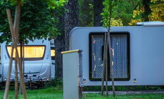 Campers Parked in Lush Greenery During Dusk With Illuminated Windows in a Serene Setting photo