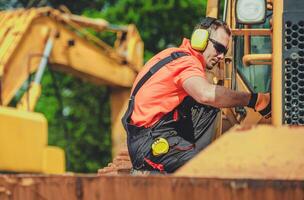Construction Worker Performing Maintenance on Heavy Machinery at a Job Site During the Day photo