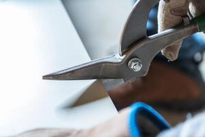 A Person Using Heavy-Duty Scissors to Cut Through a Thick Sheet of Material in a Workshop Setting photo