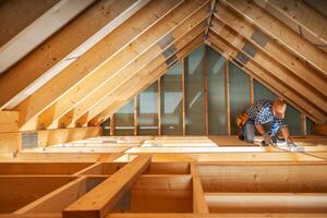 A Carpenter Working on an Attic Renovation Project With Natural Light Streaming Through the Beams photo