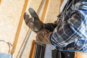 Worker Adjusts Gloves in a Workshop While Preparing for a Construction Task in the Morning Light photo