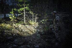A Person Exploring a Forested Area With a Flashlight During Nighttime in a Remote Location photo