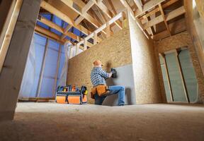 Carpenter Installing Drywall in a Newly Constructed Room During Daylight photo
