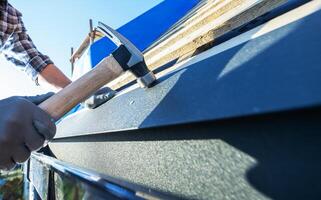A Construction Worker Hammers Roofing Materials on a Sunny Day in a Residential Building Project photo