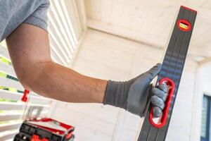 A Worker Using a Leveling Tool in a Well-Lit Indoor Space to Ensure Precise Alignment photo