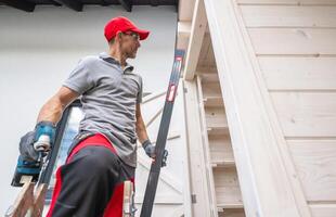 A Carpenter Using a Level Tool While Working on Wooden Structure in a Residential Area photo