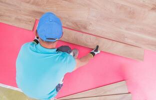 Man Installing Laminate Flooring in a Bright Room During Daylight Hours photo