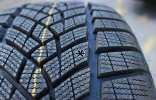 Non studded winter tyre with deep sipes and snowflake symbol on the tread block to measure tyre wear. Winter tyre for safe driving. Snow tyre with aggressive tread pattern photo