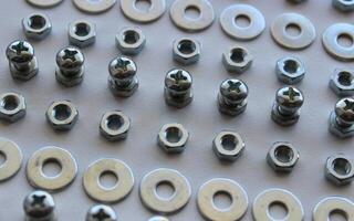Lines Of Metallic Hardware Items On A White Surface Of Workbench. Macro Shot Stock Photo For Hardware Backgrounds