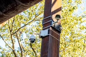 Two security cameras mounted on a rusty pole monitoring the area photo