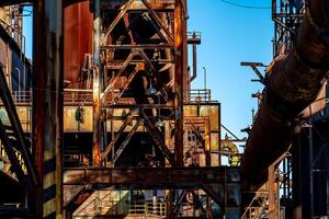 Rusty industrial structure with pipes and metal beams in an abandoned factory photo