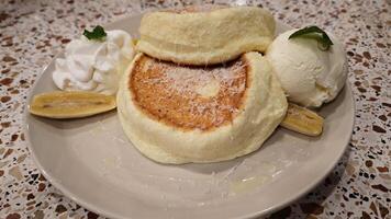 Delicious Japanese Fluffy Pancakes with Vanilla Ice Cream and Fresh Banana Slices on a Terrazzo Table photo