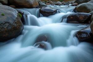 A stream of water flowing over rocks in a river photo
