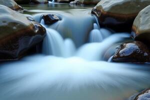 A stream of water flowing over rocks in a river photo