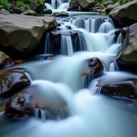 A waterfall flowing over rocks in a forest photo